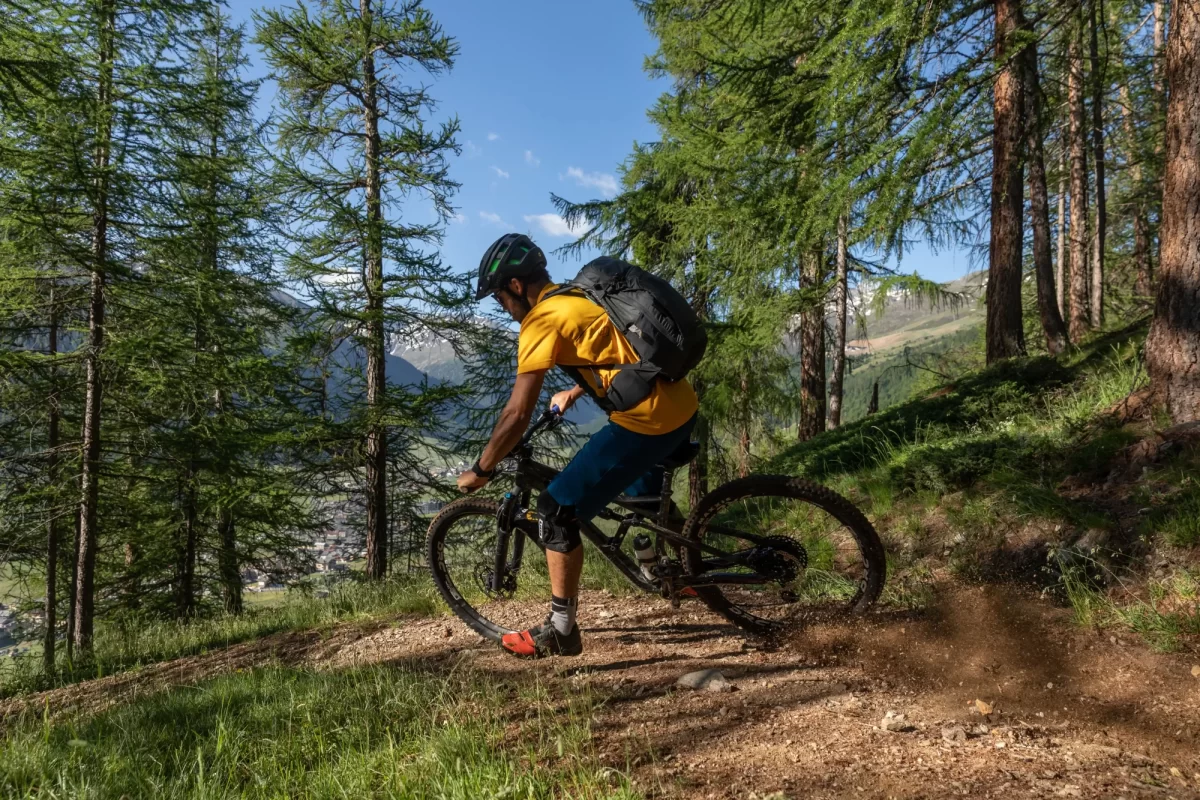 Ciclista in mountain bike su sentiero boschivo di montagna.