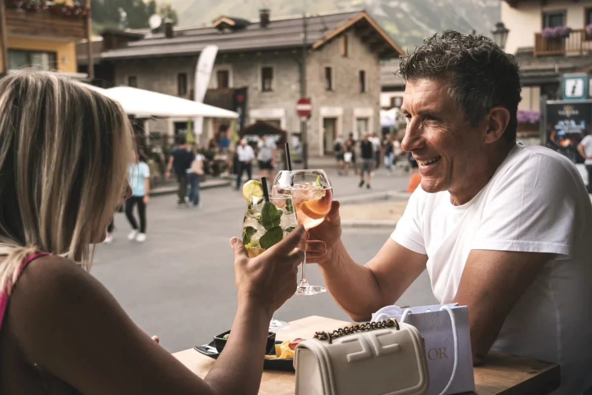 Due persone brindano all'aperto in un ambiente montano pittoresco.