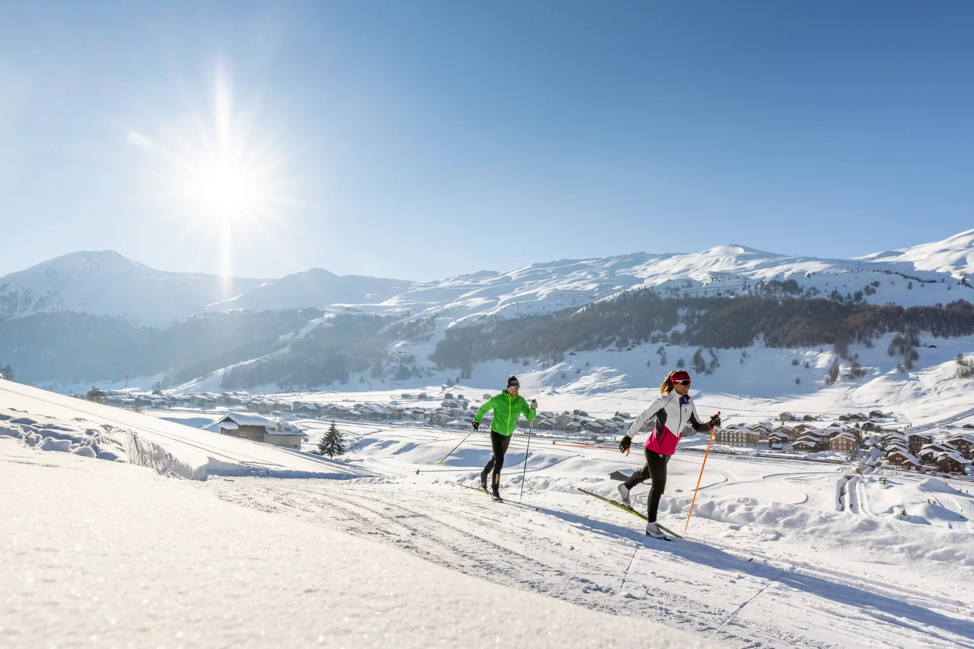 Persone che fanno sci di fondo su un pendio innevato sotto un cielo soleggiato.