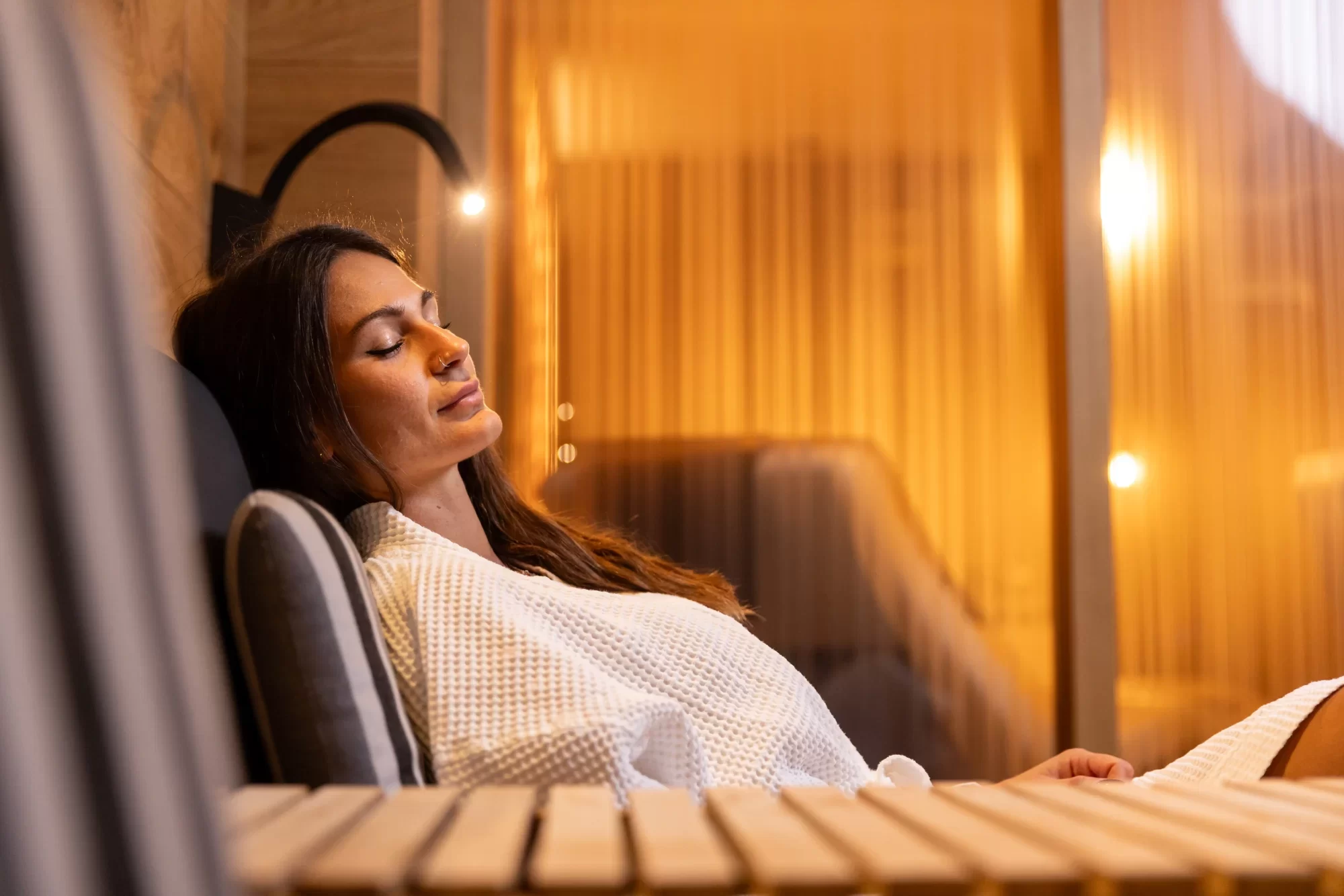 Donna rilassata in una spa con luce soffusa ambrata.
