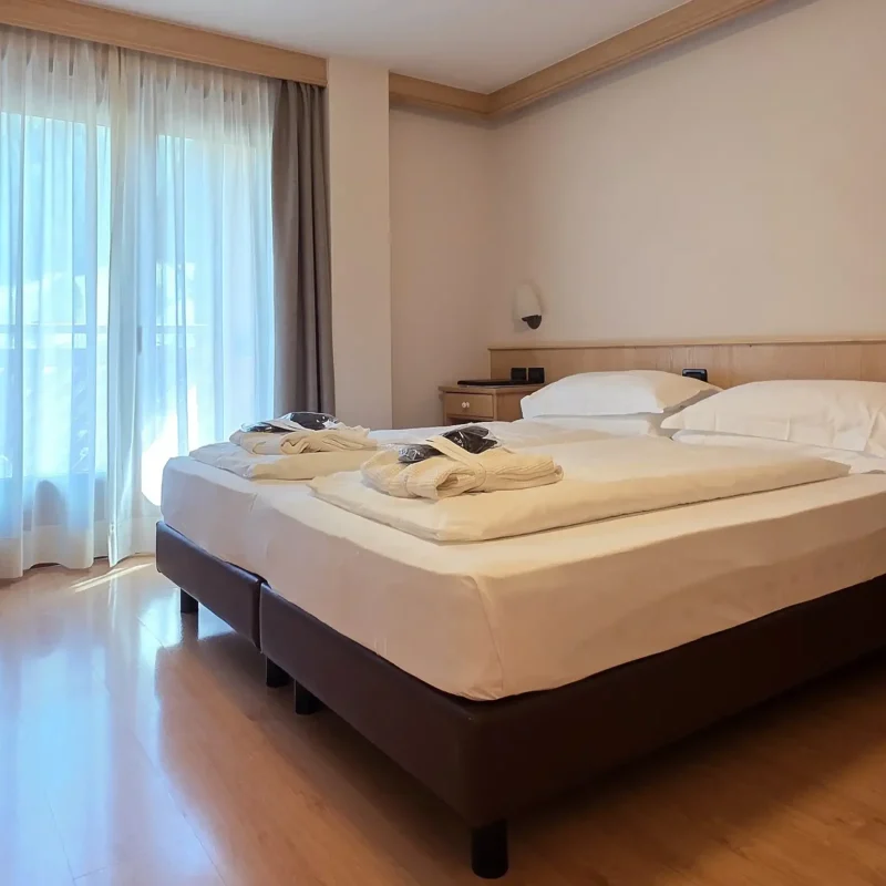 Alt: Modernes Hotelzimmer mit Doppelbett und Balkon. Title: Modernes Hotelzimmer mit Doppelbett und Balkon.