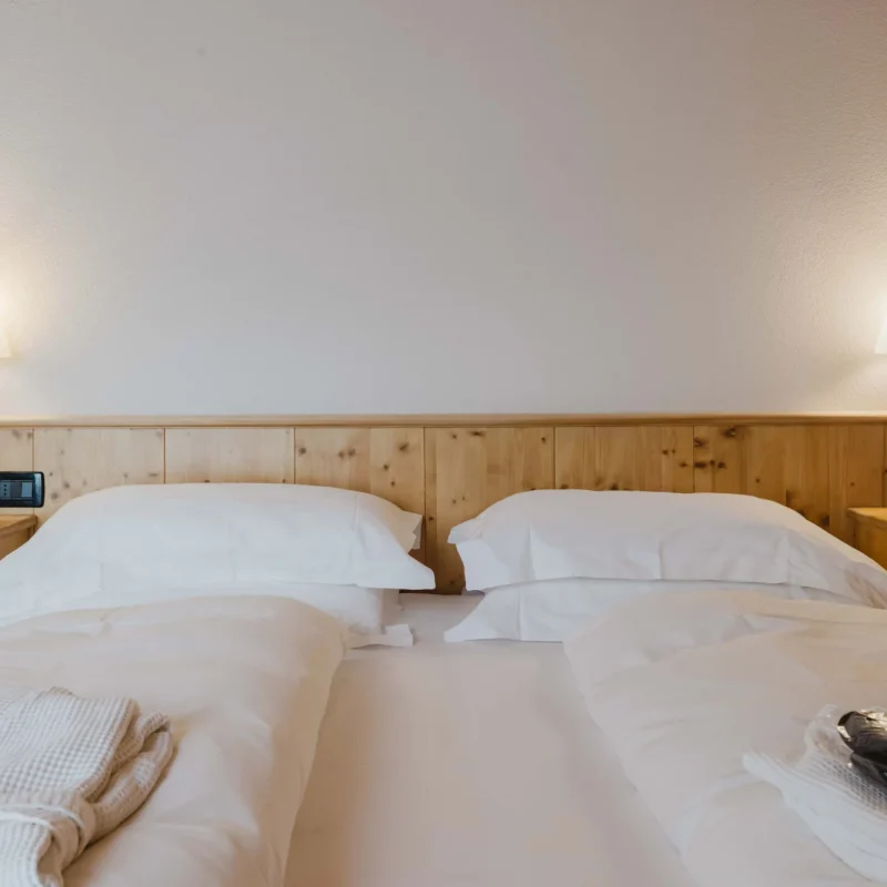 Ein gemütliches Doppelbett in einem schlicht eingerichteten Hotelzimmer mit zwei Nachttischlampen.