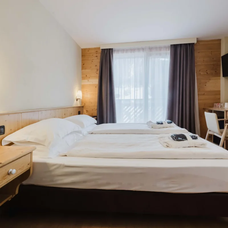 Ein gemütliches Hotelzimmer mit zwei Betten, einem Schreibtisch und einem Fernseher an der Wand.
