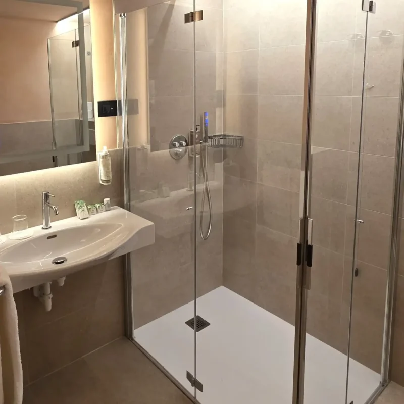 Alt und Title: Modernes Badezimmer mit einer Glasdusche und einem Waschbecken.