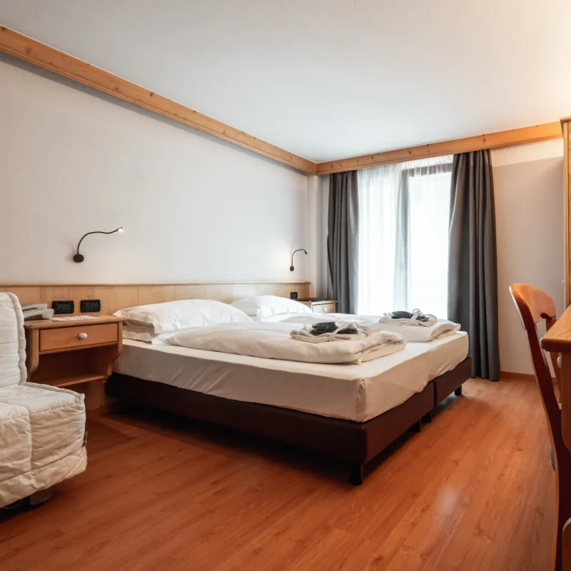 Alt: Gemütliches Hotelzimmer mit Doppelbett und Holzinterieur. Title: Gemütliches Hotelzimmer mit Doppelbett und Holzinterieur.