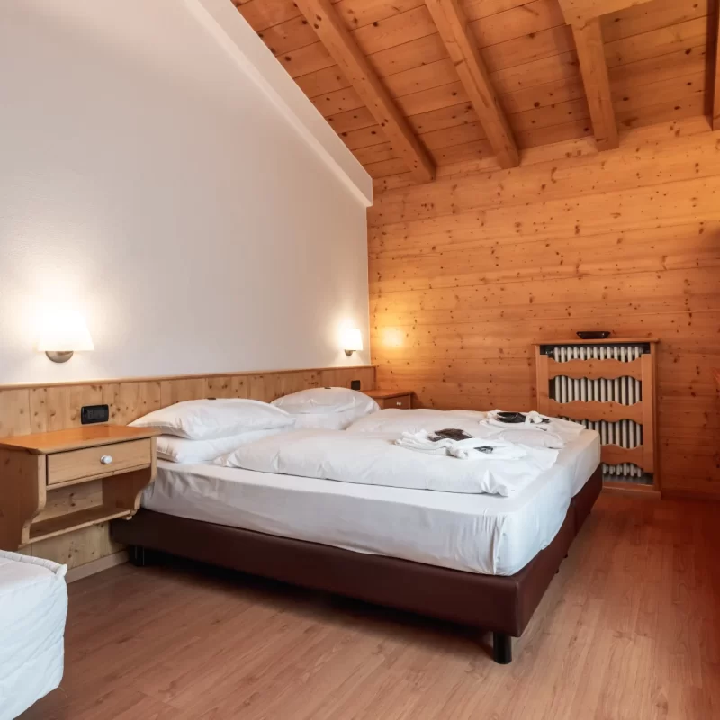 Gemütliches Schlafzimmer mit Holzmöbeln, Doppelbett und Wandfernseher.