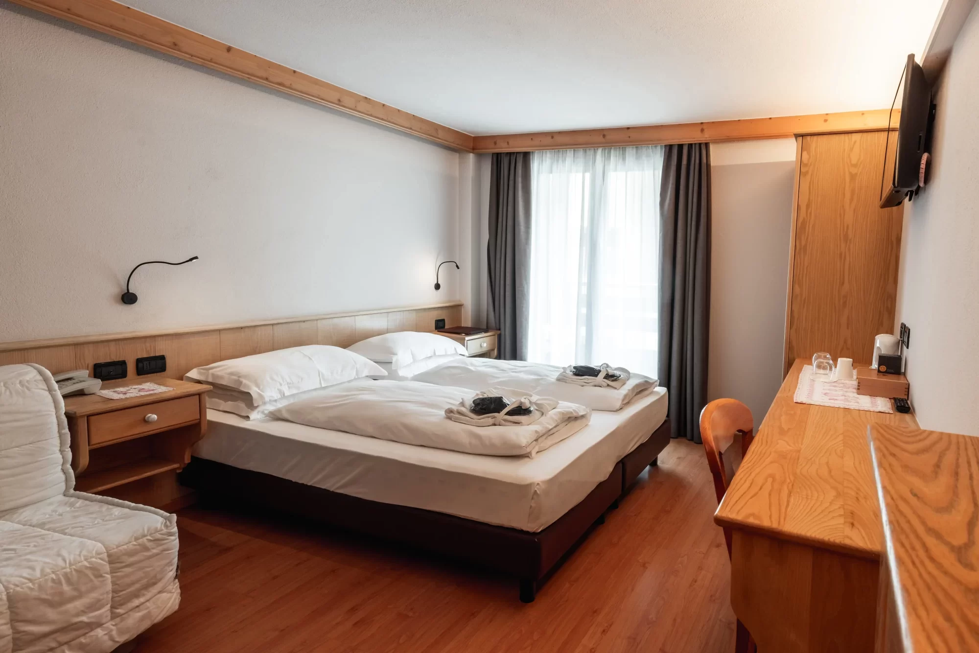 Camera d'albergo accogliente con due letti singoli e arredamento in legno.