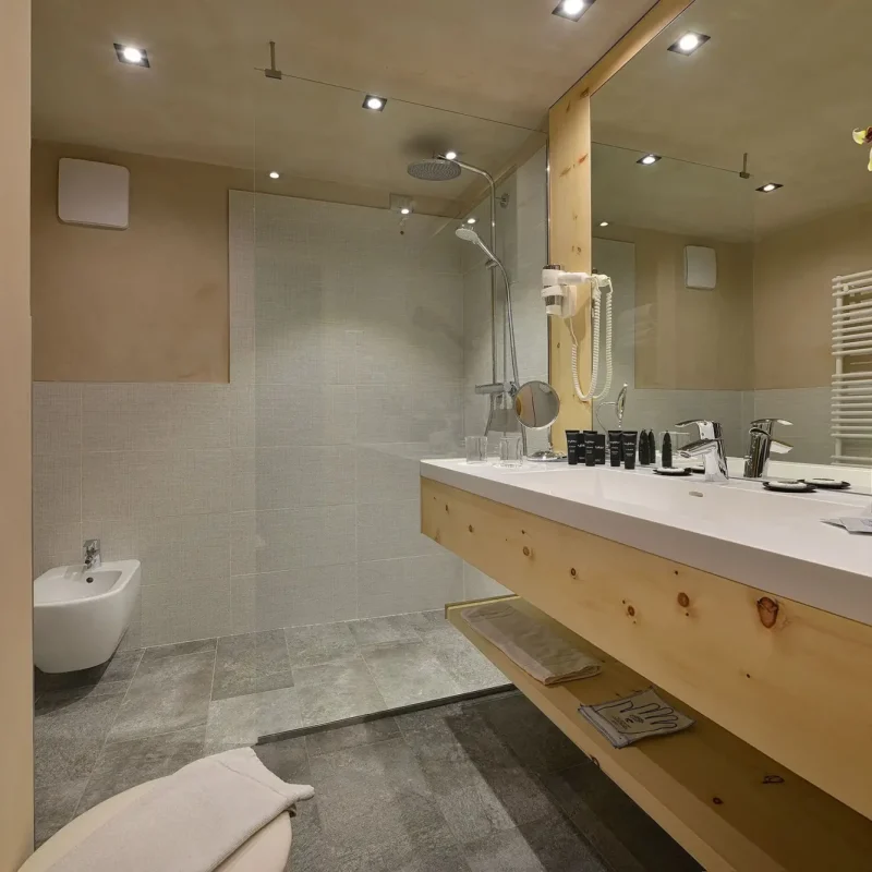 Ein modernes Badezimmer mit großen Spiegeln, Holzverkleidung und weißen Handtüchern.