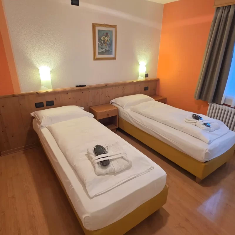 Gemütliches Hotelzimmer mit zwei Einzelbetten, gedämpfter Beleuchtung und Holzmöbeln.