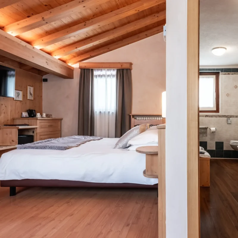 Gemütliches Schlafzimmer mit Holzdekor und angrenzendem Badezimmer.