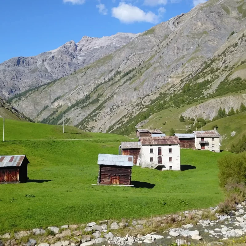 Altes Bergdorf mit malerischen Häusern und grünen Wiesen in den Alpen.