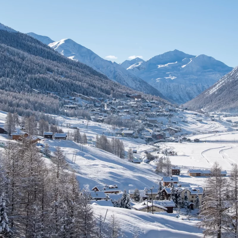 Verschneite Berglandschaft mit einem Dorf im Tal.