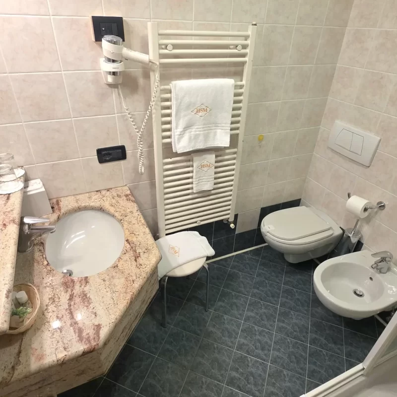 Modernes Badezimmer mit Waschbecken, Bidet, WC und Handtuchhalter.