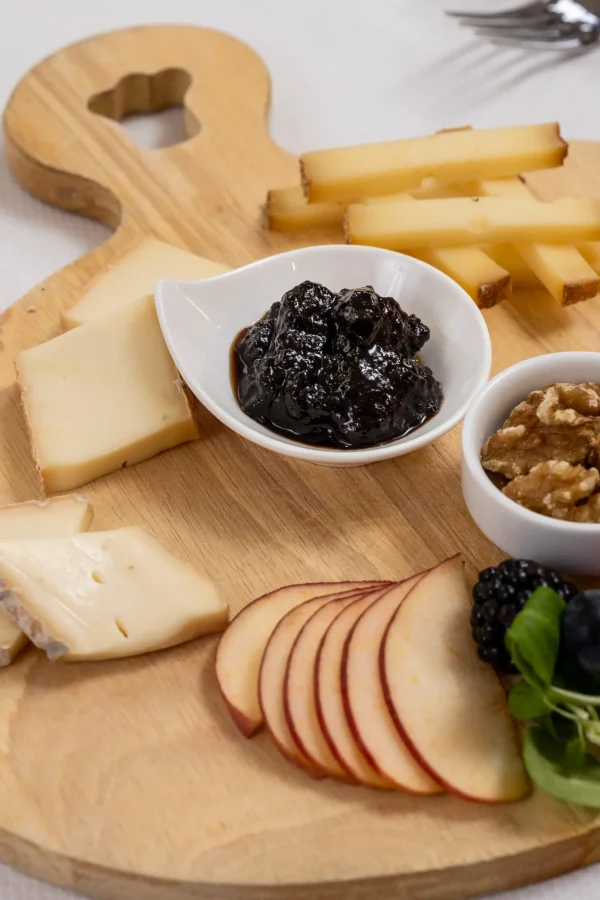 Tagliere di formaggi misti con marmellata, noci e frutta.