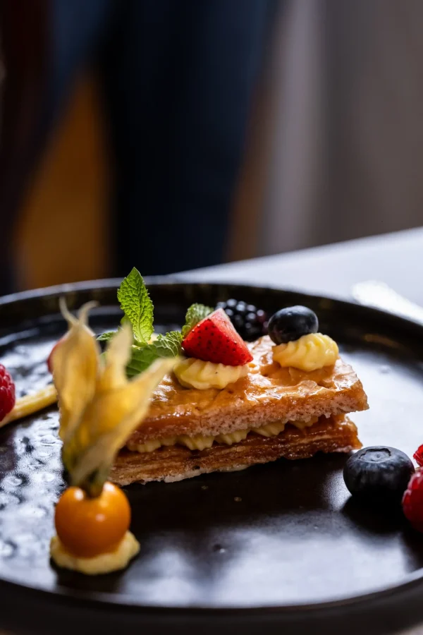 Dessert al piatto con millefoglie, crema pasticcera e frutti di bosco.