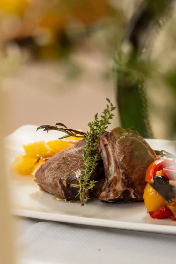 Un piatto di costolette d'agnello servite con erbe aromatiche e verdure grigliate.