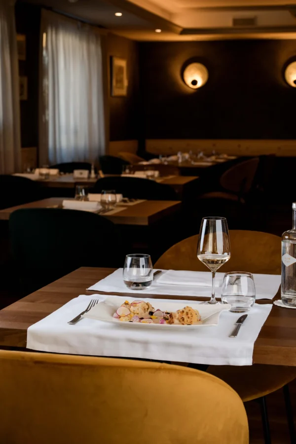 Tavolo di un elegante ristorante con piatti raffinati e calice di vino.