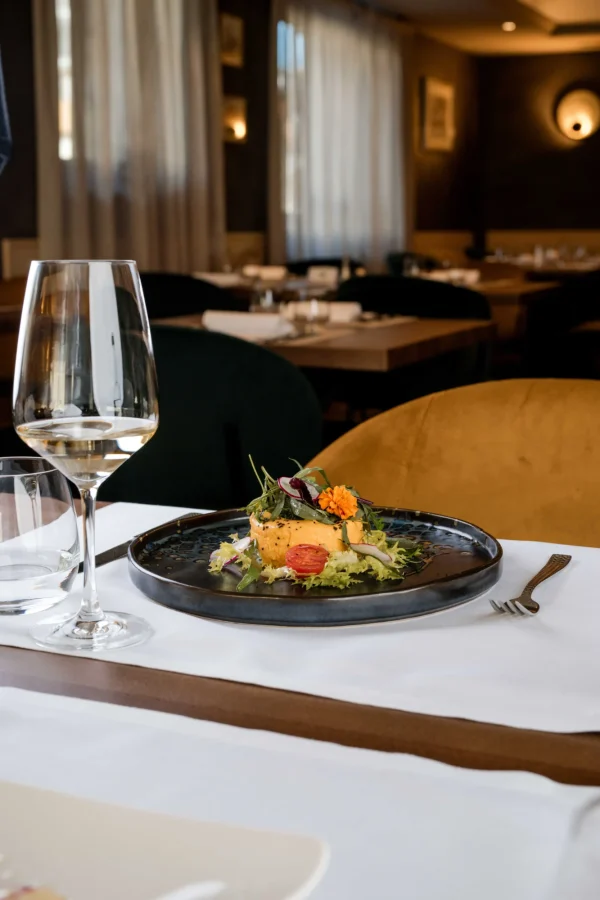 Piatti gourmet con bicchiere di vino su tavola in un ristorante elegante.
