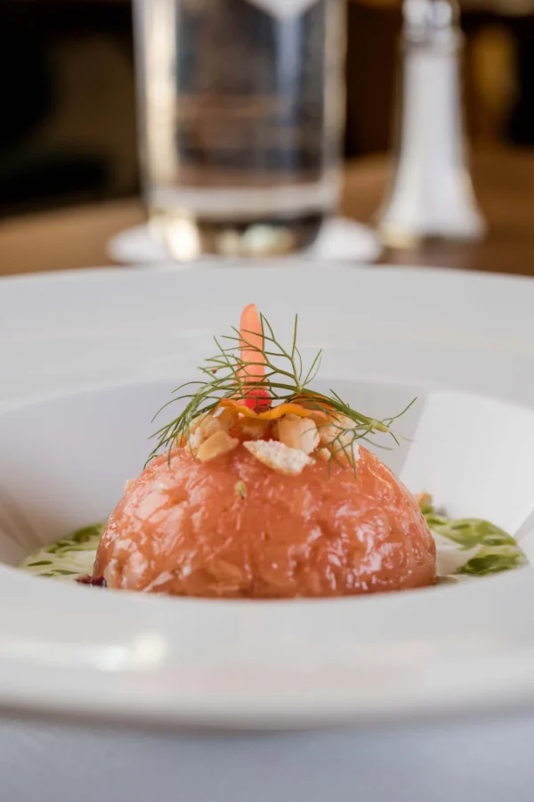 Piatto gourmet con semifreddo decorato con erbe e granella di noci.