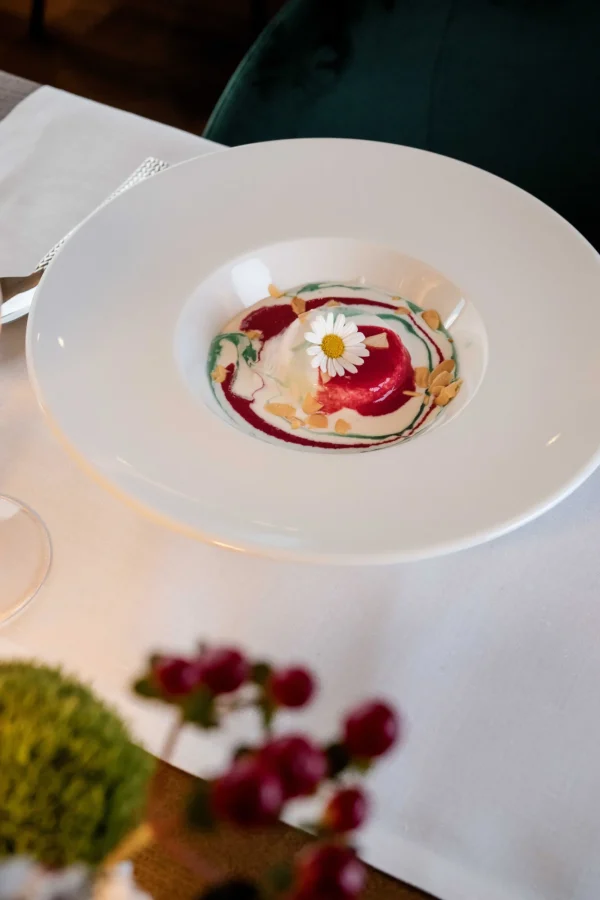 Dessert gourmet decorato con una margherita su una base colorata di salse.