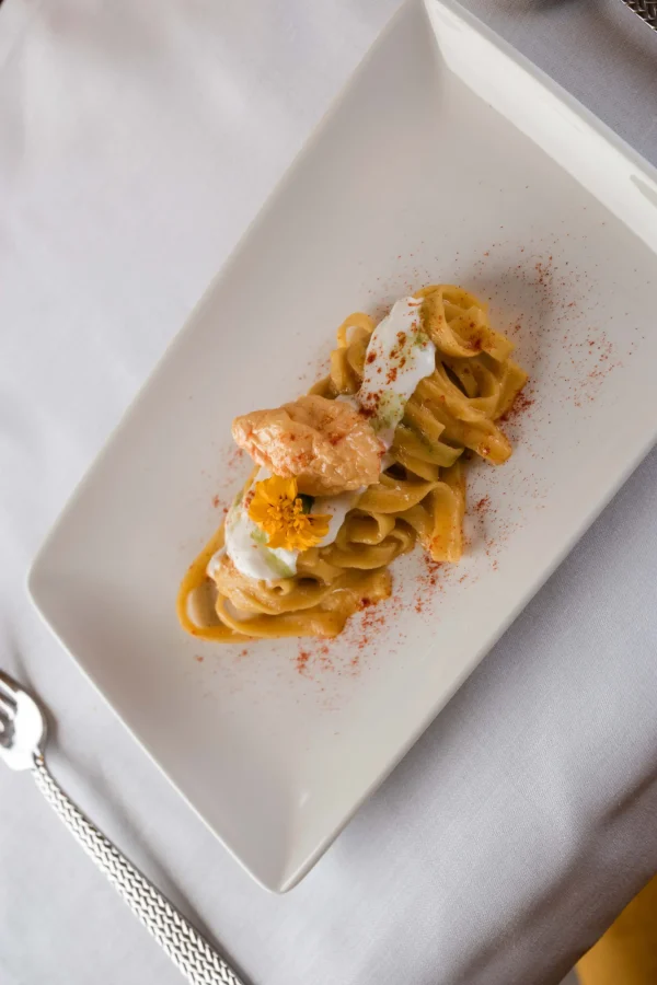 Piatto di tagliatelle con gamberetti e crema su piatto bianco.