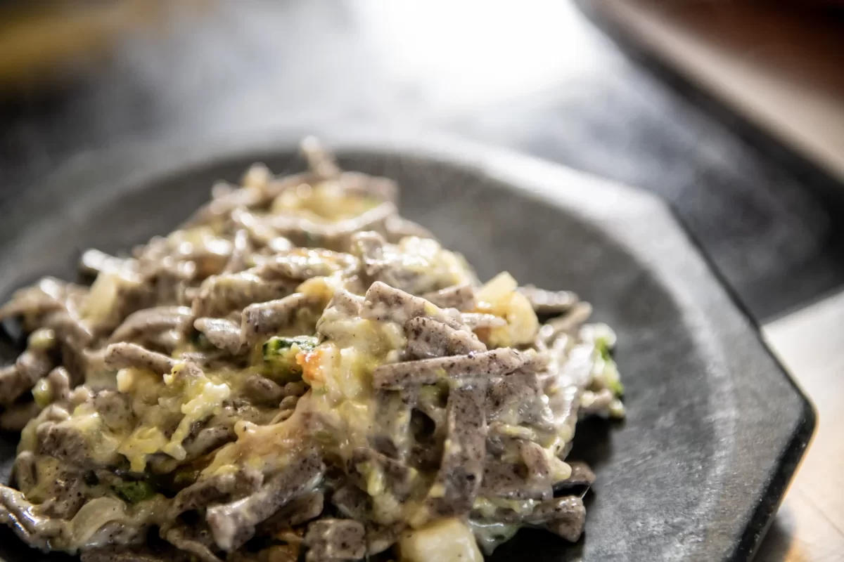 Piatto di pizzoccheri servito su un piatto di ceramica.