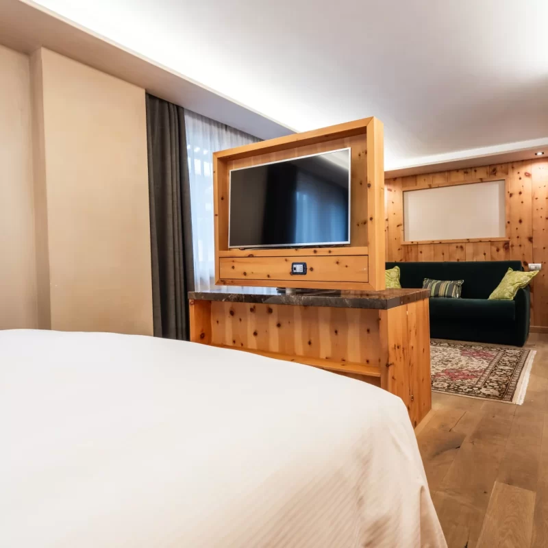 Modernes Hotelzimmer mit Bett, Flachbildfernseher und Sofa auf Holzboden.