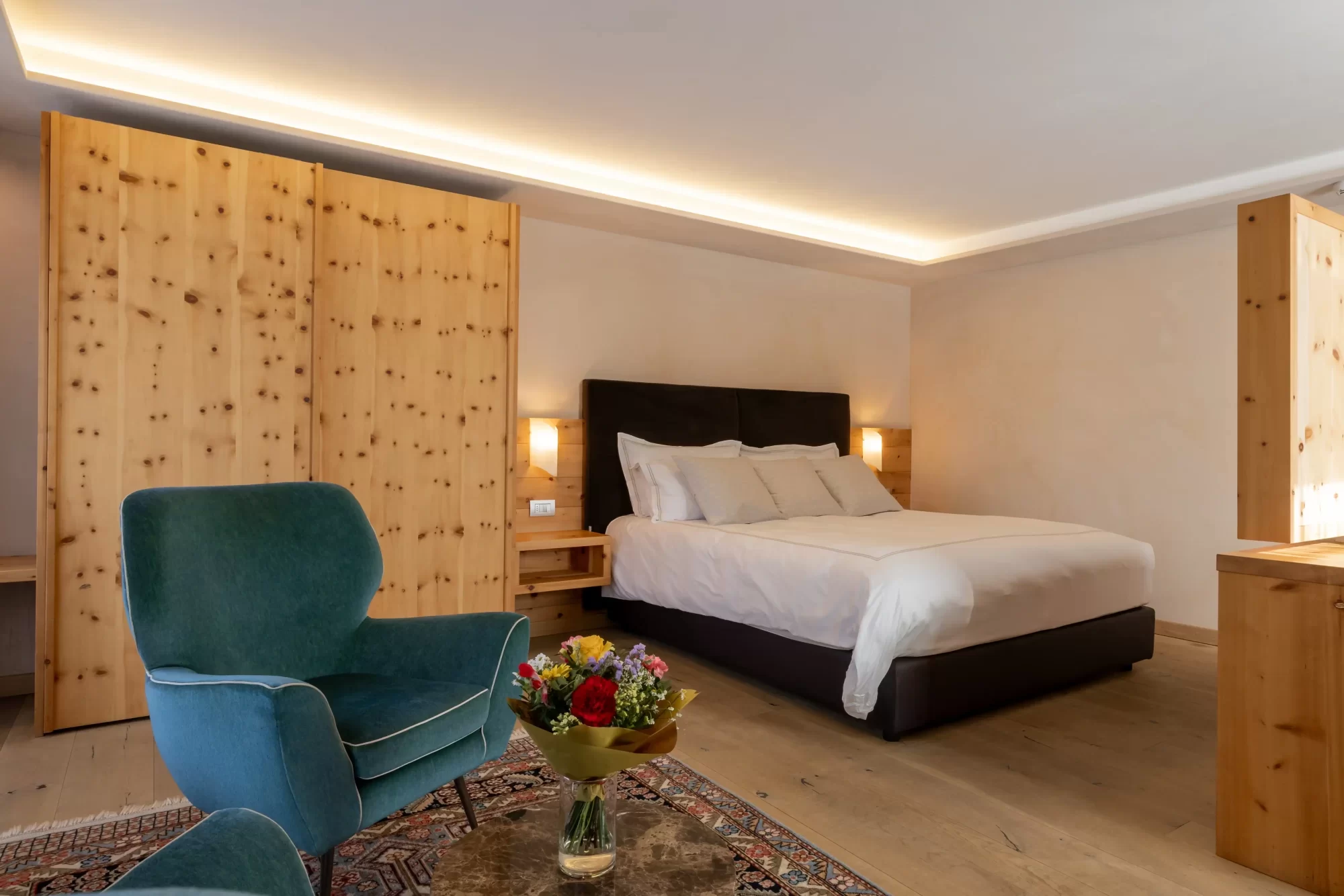 Camera da letto elegante con letto matrimoniale, poltrona verde e mobili in legno.