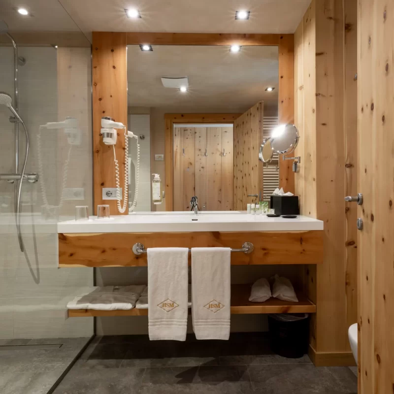 Modernes Badezimmer mit Waschbecken aus hellem Holz und Glasdusche.