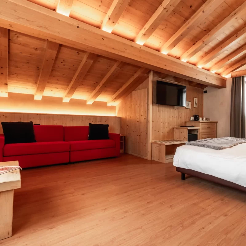Gemütliches Schlafzimmer mit Holzdecke, rotem Sofa und moderner Einrichtung.
