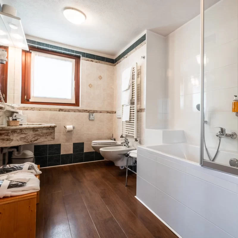 Modernes Badezimmer mit weißer Badewanne, Bidet und hellen Fliesen.