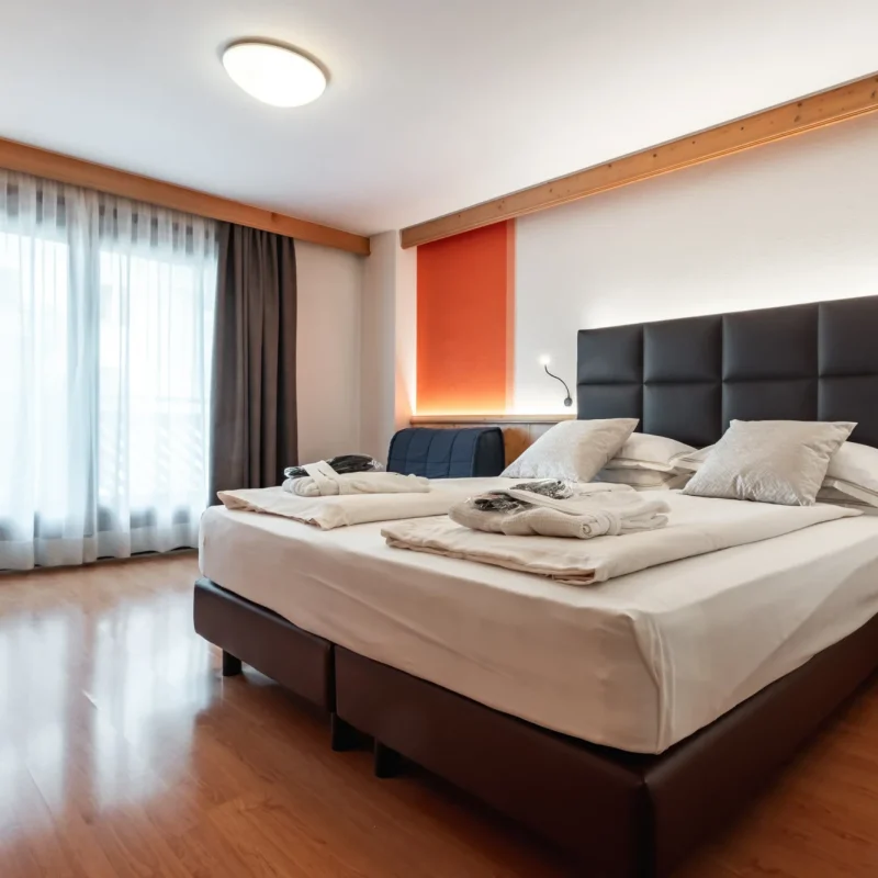Eine moderne Hotelzimmeransicht mit Doppelbett, Fenstern und Gardinen.
