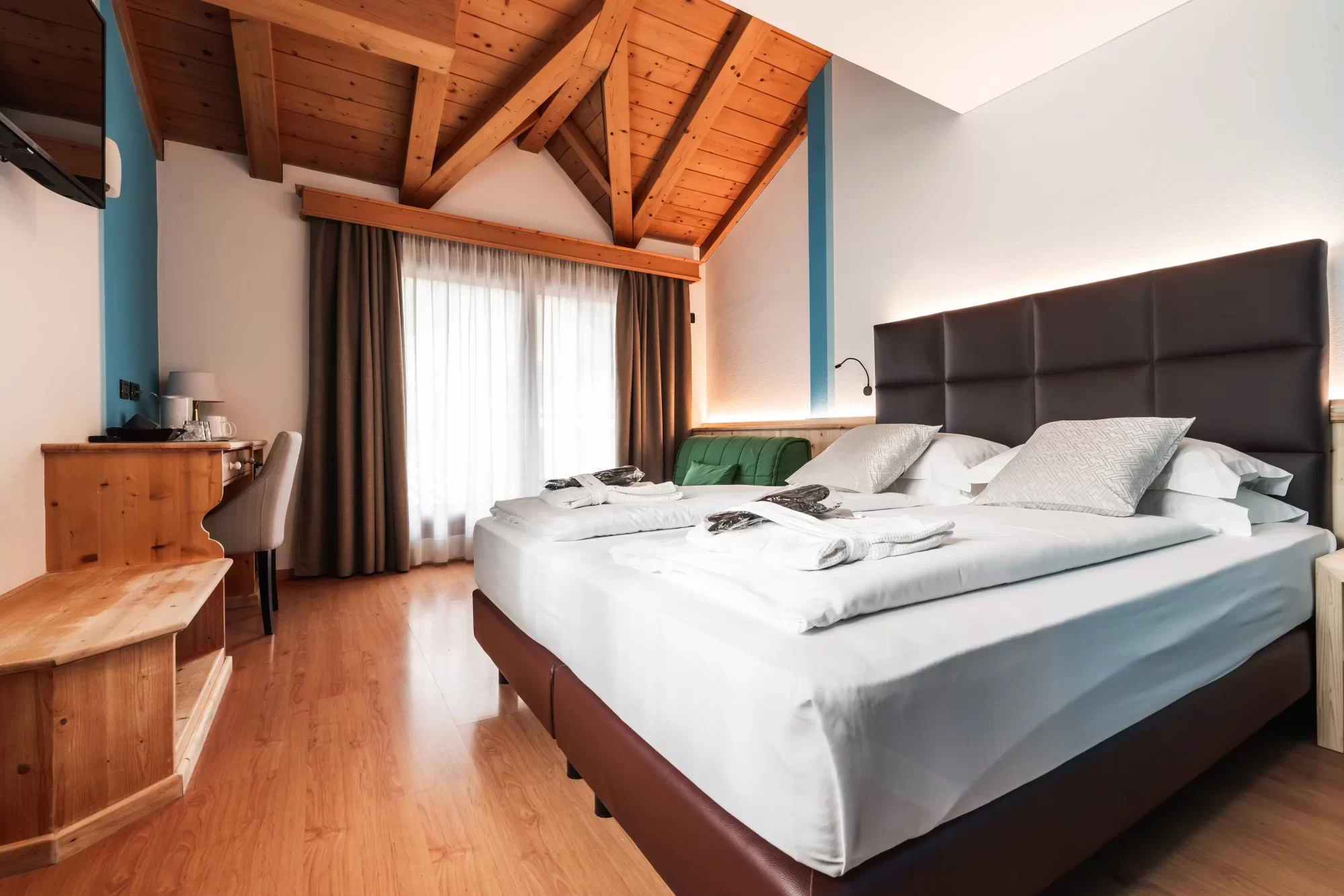 Camera da letto moderna con soffitto in legno e ampio letto matrimoniale.